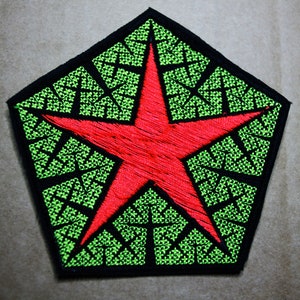 May include: A red star with a green geometric pattern in the background. The star is embroidered on a black fabric patch.