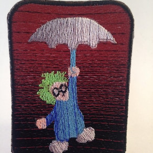 May include: Embroidered patch featuring a whimsical figure holding an umbrella. The figure has green hair, glasses, and a blue outfit. The umbrella is silver, and the background is a gradient of red and black.