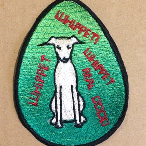 May include: Green and white embroidered patch with a white whippet dog sitting on a green background. The text "Whippet Real Good" is embroidered in red around the dog.