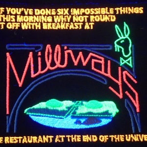 Puede incluir: Un letrero de neón con el texto "IF YOU'VE DONE SIX IMPOSSIBLE THINGS THIS MORNING WHY NOT ROUND IT OFF WITH BREAKFAST AT" y "Millways THE RESTAURANT AT THE END OF THE UNIVERSE". El letrero es rojo, azul, verde y amarillo.