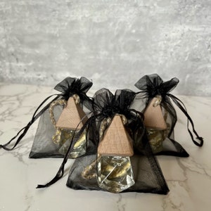 May include: Three small glass bottles with gold glitter inside, each with a wooden triangular stopper and a black mesh drawstring bag.