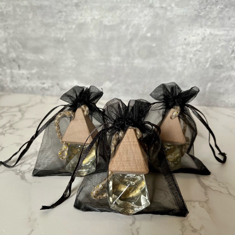 May include: Three small glass bottles with gold glitter inside, each with a wooden triangular stopper and a black mesh drawstring bag.