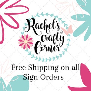 May include: A white background with a floral wreath design in blue and pink. The wreath surrounds the text "Rachel's Crafty Corner" in black. Below the wreath, the text "Free Shipping on all Sign Orders" is in black.