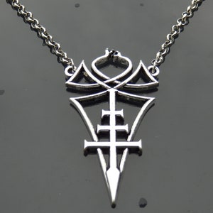 Puede incluir: Collar con colgante de plata con un diseño detallado e intrincado que presenta una cruz y una forma puntiaguda. El colgante está suspendido de una cadena de plata.