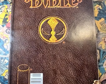 May include: A comic book titled "Spawn Bible" with a brown leather-like cover. The title is in gold lettering, and a gold emblem is centered on the cover. The comic book is issue number 1, with a price of $1.95.