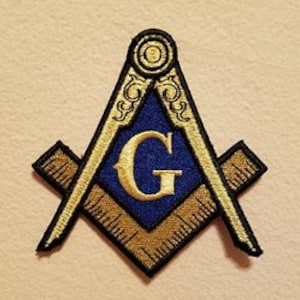 May include: Embroidered patch depicting the Masonic Square and Compasses symbol. The patch features a blue centre with a gold "G", framed by gold and black detailing. The background is a light tan colour.