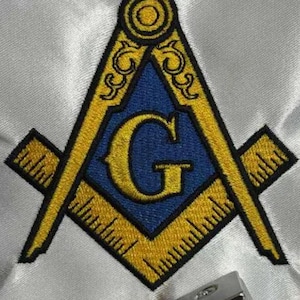 May include: Embroidered Masonic symbol. The design features a yellow square and compass with a blue centre and the letter "G". The symbol is set against a white fabric background.