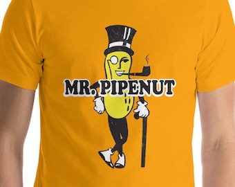 May include: A yellow t-shirt featuring a cartoon image of Mr. Peanut wearing a top hat, monocle, and smoking a pipe. The text "MR. PIPENUT" is printed in black below the image.