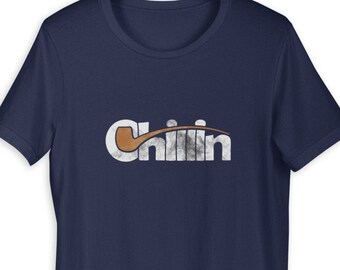 May include: Navy blue t-shirt with a white and grey "Chillin" graphic featuring a brown pipe design.