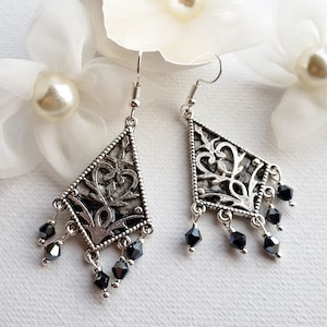 May include: Silver dangle earrings with a geometric design and black crystal accents.