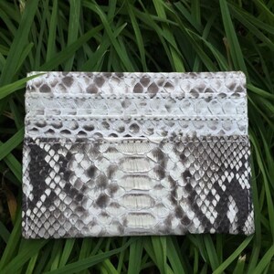 May include: A white and gray snakeskin card holder with multiple card slots.