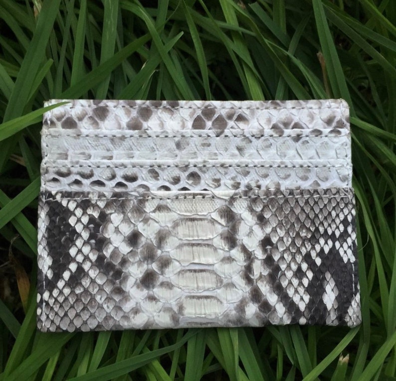 May include: A white and gray snakeskin card holder with multiple card slots.