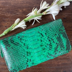 以下が含まれることがあります： 表面がテクスチャ加工された緑色のヘビ革クラッチバッグ
