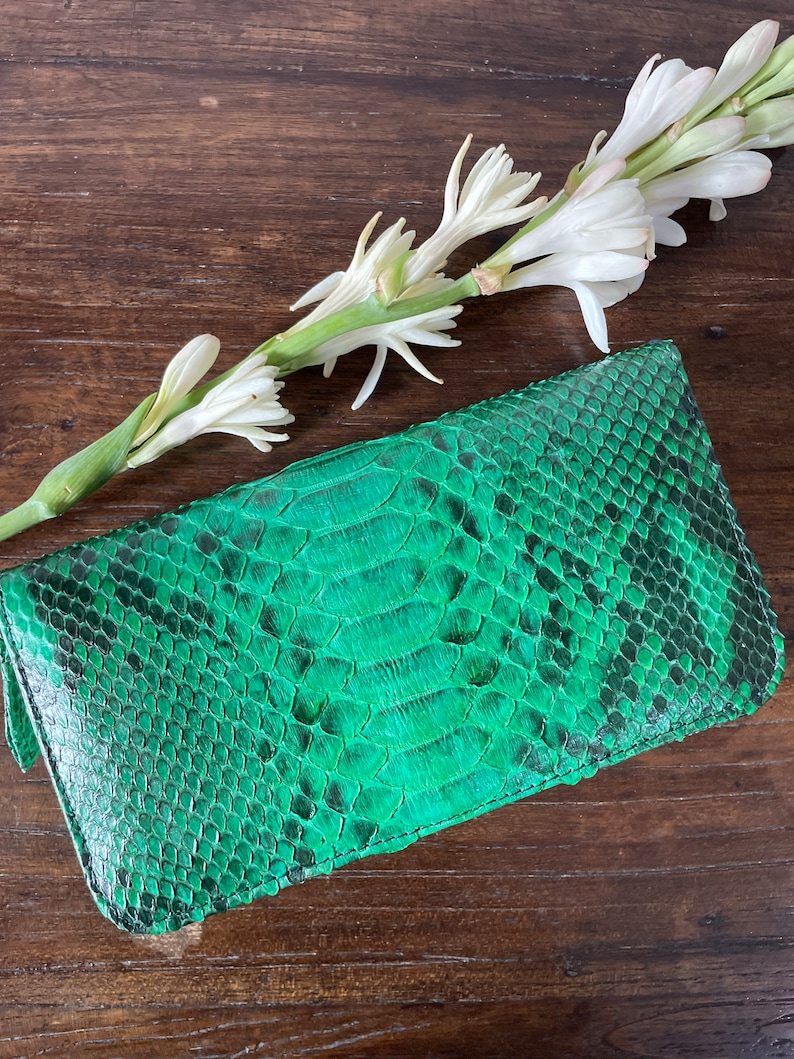 以下が含まれることがあります： 表面がテクスチャ加工された緑色のヘビ革クラッチバッグ