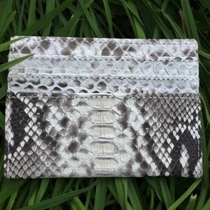 May include: A white and black snakeskin card holder with multiple card slots.