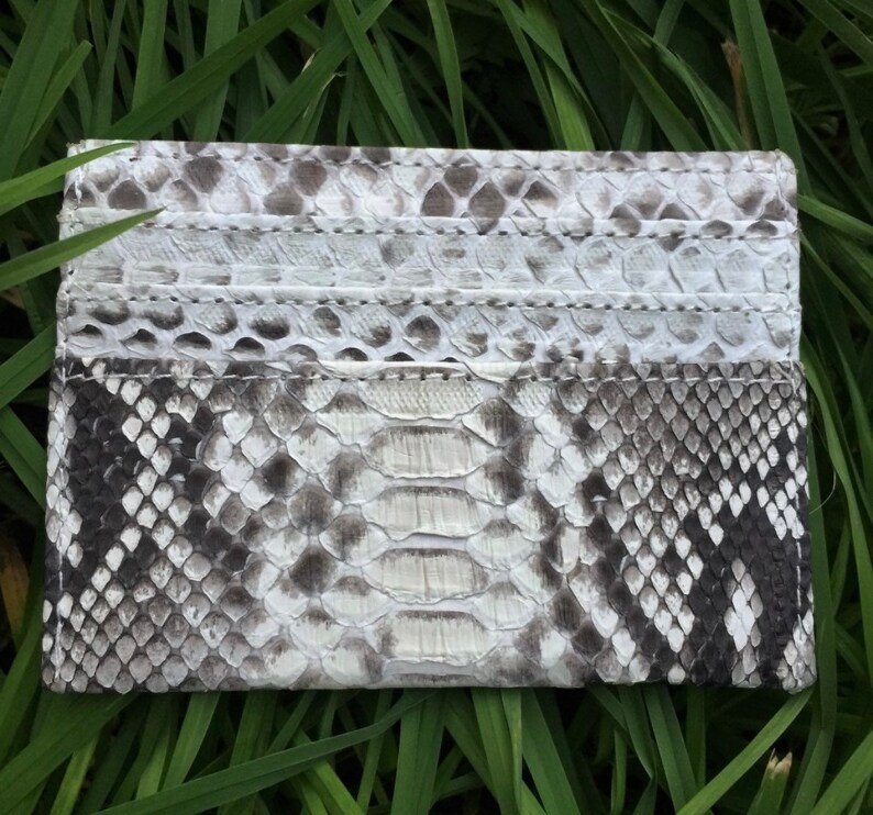 May include: A white and black snakeskin card holder with multiple card slots.