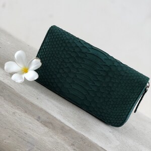 以下が含まれることがあります： ジッパー付きの濃い緑色のヘビ革財布