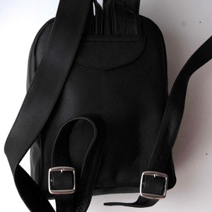 以下が含まれることがあります： 調節可能なストラップとシルバーのバックルが付いた黒い革のバックパック。バックパックには前面に小さなポケットがあります。