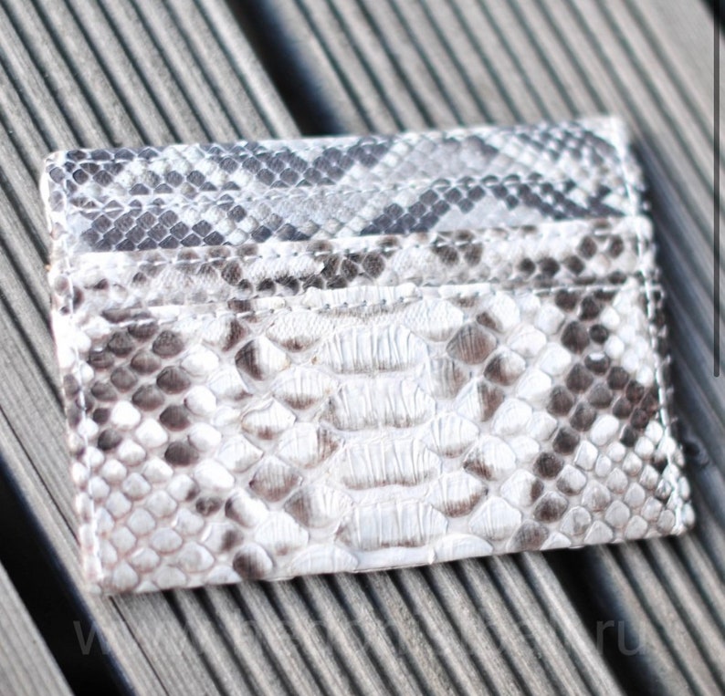 May include: A gray and white snakeskin card holder with a textured surface.
