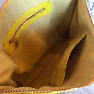May include: The inside of a yellow leather handbag with a zippered pocket and a smaller pocket on the side.