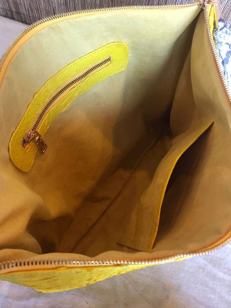 May include: The inside of a yellow leather handbag with a zippered pocket and a smaller pocket on the side.