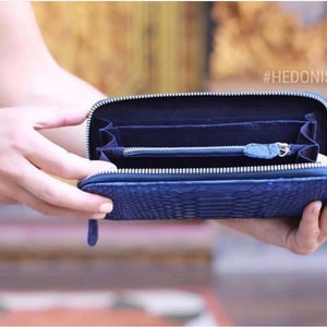 May include: A blue leather wallet with a zipper closure and a snakeskin pattern. The wallet is open and empty, showing the interior lining. The text #HEDONIST is visible in the top right corner of the image.