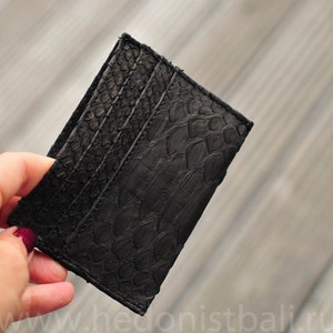 Puede incluir: Porta tarjetas de cuero negro con un patr&oacute;n texturizado y estampado. El porta tarjetas tiene m&uacute;ltiples ranuras para tarjetas.