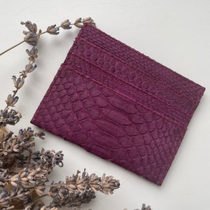 K&ouml;nnte beinhalten: Ein Kartenetui aus violettem Leder mit einem strukturierten Muster, das an Schlangenhaut erinnert.