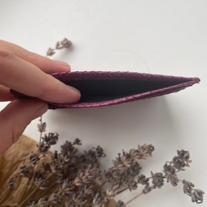 K&ouml;nnte beinhalten: Ein Kartenetui aus violettem Leder mit strukturierter Oberfl&auml;che. Das Kartenetui ist offen und leer.