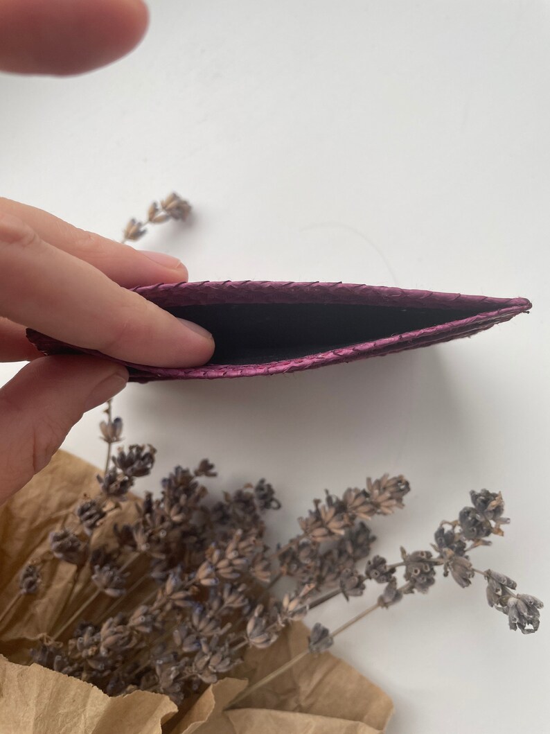 K&ouml;nnte beinhalten: Ein Kartenetui aus violettem Leder mit strukturierter Oberfl&auml;che. Das Kartenetui ist offen und leer.