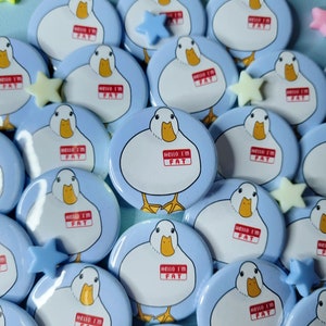 Peut inclure: Une collection de boutons ronds bleus et blancs avec un canard de dessin animé portant une étiquette avec l'inscription "Hello I'm Fat".