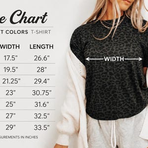 K&ouml;nnte beinhalten: Gr&ouml;&szlig;entabelle f&uuml;r Comfort Colors T-Shirts, mit Ma&szlig;en in Zoll. Die Tabelle enth&auml;lt die Gr&ouml;&szlig;en S bis 4XL und gibt Breite und L&auml;nge an. Eine Frau tr&auml;gt ein dunkelgraues T-Shirt mit Leopardenmuster.