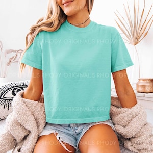 May include: A turquoise blue cropped t-shirt with short sleeves. The shirt is made of a soft, comfortable material and has a relaxed fit.