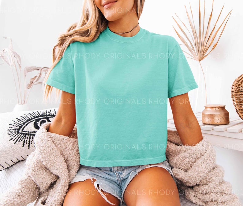 May include: A turquoise blue cropped t-shirt with short sleeves. The shirt is made of a soft, comfortable material and has a relaxed fit.