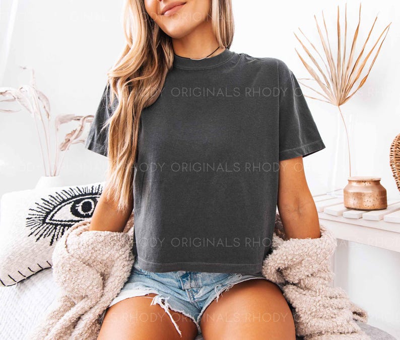 May include: A dark gray cropped t-shirt with a relaxed fit and short sleeves. The shirt has a slightly distressed look and is made of a soft, comfortable fabric.