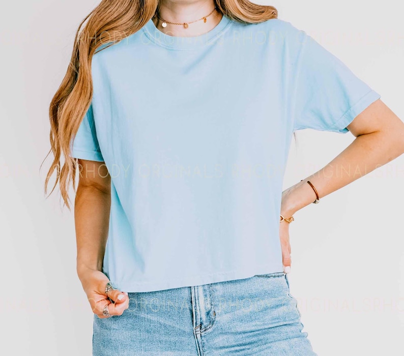 May include: A light blue cropped t-shirt with short sleeves. The shirt is made of a soft, comfortable fabric and has a relaxed fit.