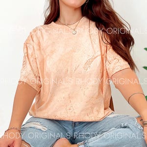 May include: A peach-coloured tie-dye t-shirt with a short sleeve and a relaxed fit. The shirt is made of a soft, comfortable material and has a subtle tie-dye pattern.
