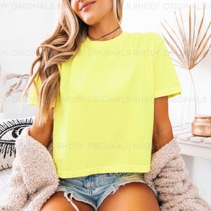 May include: A bright yellow cropped t-shirt with short sleeves. The shirt is made of a soft, comfortable fabric and has a relaxed fit.