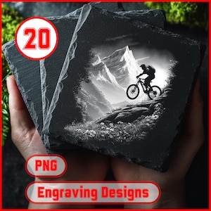 May include: Three square slate coasters featuring a mountain biking scene. The black and white image shows a cyclist on a mountain trail with a mountainous backdrop. The coasters are held in a person's hands. The image also includes the text "Engraving Designs".