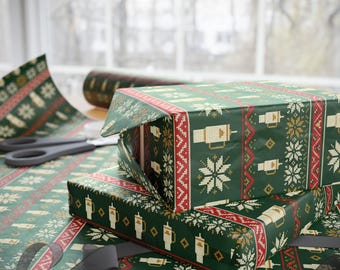 May include: Dark green wrapping paper featuring a repeating pattern of white snowflakes, red geometric stripes, and small beige tumbler cups with straws. The paper is shown wrapped around rectangular boxes with a roll nearby.