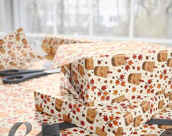 May include: Wrapping paper featuring a repeating pattern of cartoon bubble tea cups with smiling faces, interspersed with orange and red autumn maple leaves, small brown acorns, and tiny mushrooms on a light cream-colored background.