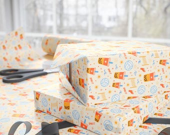 May include: Wrapping paper featuring a repeating pattern of orange boba tea cups, blue volleyballs, yellow volleyball nets, and orange hands on a cream background. The text "SPIKE IT" is printed in orange next to the boba tea cup illustrations.