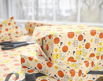 May include: Wrapping paper with a repeating pattern of orange basketballs, yellow smiling bubble tea cups, basketball hoops, and blue sneakers on a cream background. The paper is wrapped around two rectangular boxes with black scissors nearby.
