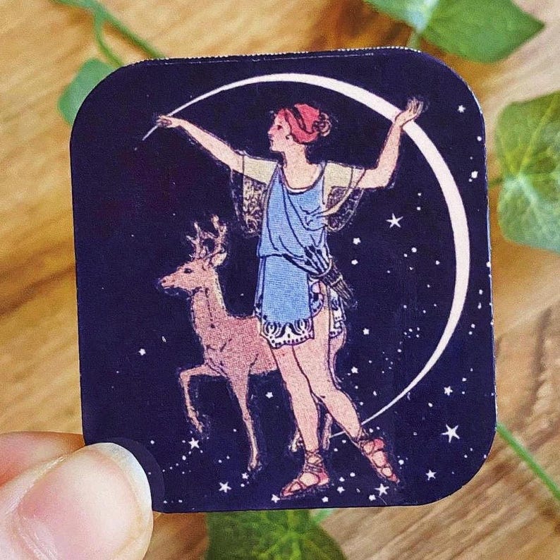 May include: A square sticker featuring a celestial design. It depicts a woman in a blue dress, a deer, and a crescent moon against a dark blue starry background. The woman is holding a wand, and the deer is standing beside her.