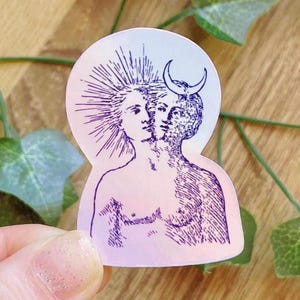Könnte beinhalten: Ein Aufkleber mit einem himmlischen Design, das eine Figur mit zwei Gesichtern darstellt. Die Illustration ist in Lila und Weiß gehalten, mit einem Sonnenstrahl auf der einen und einem Halbmond auf der anderen Seite. Der Aufkleber hat einen Farbverlauf.
