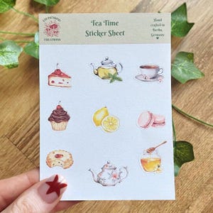 Könnte beinhalten: Ein Stickerbogen mit dem Thema Teezeit. Der Bogen zeigt Illustrationen einer Teekanne, einer Teetasse, Kuchen, Cupcakes, Zitrone, Makronen, Honig und einer Torte. Der Text "Tea Time Sticker Sheet" ist oben aufgedruckt.