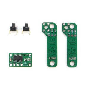 Könnte beinhalten: Elektronische Komponenten, darunter zwei schwarze Drucktasten, eine kleine grüne Leiterplatte mit Text und zwei grüne Leiterplatten mit japanischem Text. Die Komponenten sind auf weißem Hintergrund angeordnet.