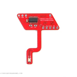 Może przedstawiać: Czerwona płytka drukowana z napisem "TYPE D CONSOLES UNLEASHED MULTI-REGION SATURN" oraz różnymi elementami elektronicznymi. Płytka ma unikalny kształt z prostokątnym wierzchem i wąskim, zakrzywionym przedłużeniem.