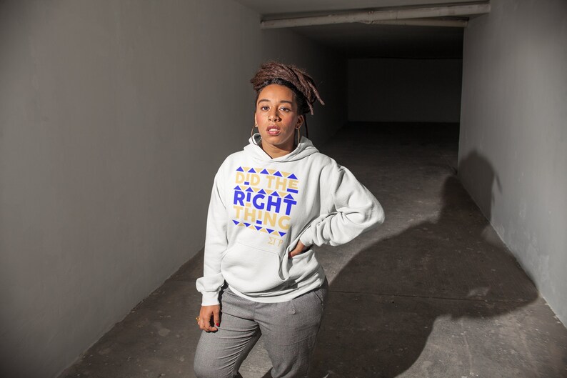 May include: A white hooded sweatshirt with the text "Did the Right Thing" in gold and blue lettering. The text is surrounded by a pattern of gold and blue triangles.