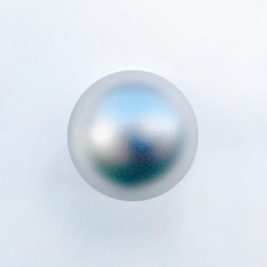 Può includere: Una sfera argentata con finitura opaca, che riflette la luce e il colore. La palla ha una forma rotonda e solida e sembra essere fatta di metallo. L'oggetto è posto su uno sfondo bianco.